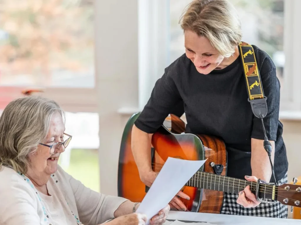 A Music Facilitator sharing sheet music with a resident during a session
